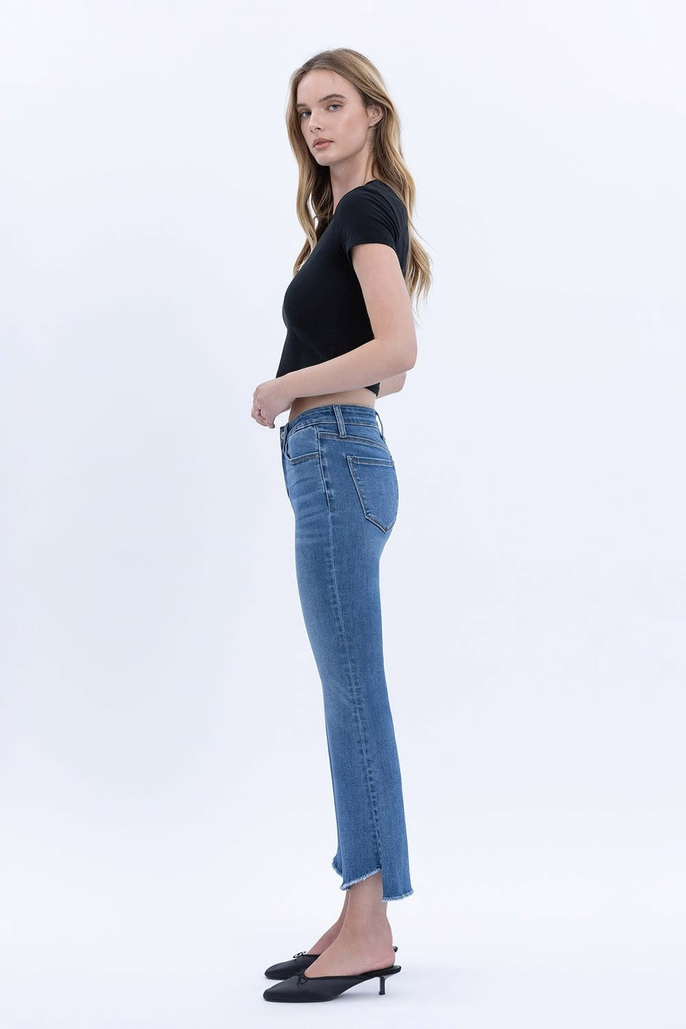 Side view of mid-rise raw hem crop flare jeans in stretch denim with a cropped length and flared silhouette.
