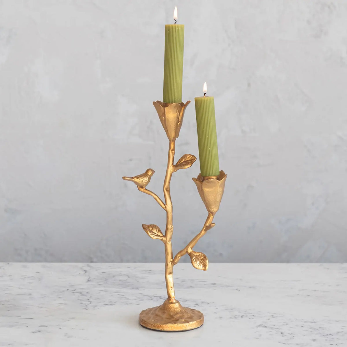 Gold cast iron candelabra featuring a bird perched among floral silhouettes.