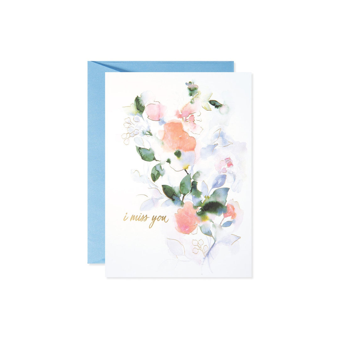 A watercolor greeting card with pink and blue flowers and the text 'i miss you' in gold script.