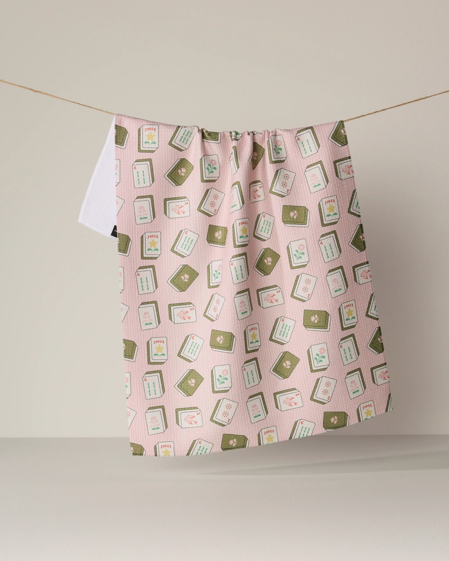 Pink Everyday Tea Towel with a green and white mahjong tile pattern hanging on a clothesline.