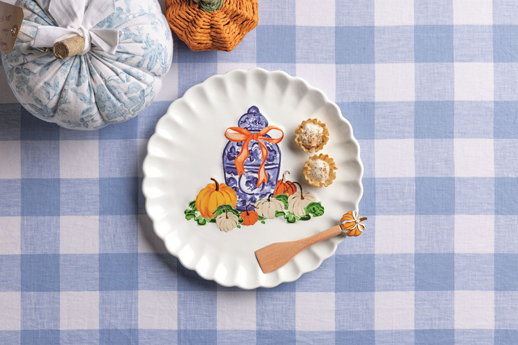 Scalloped white ceramic cookie plate with pumpkin and ginger jar design, plus a wooden spreader.