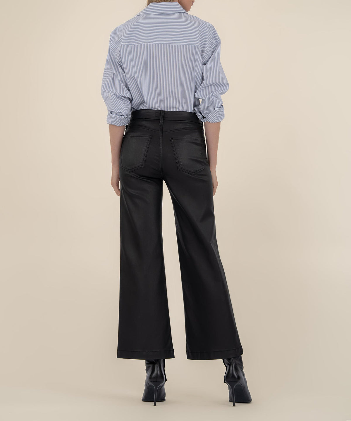 Rear view of a person wearing black high-rise wide-leg pants with a wide hem and a striped shirt.