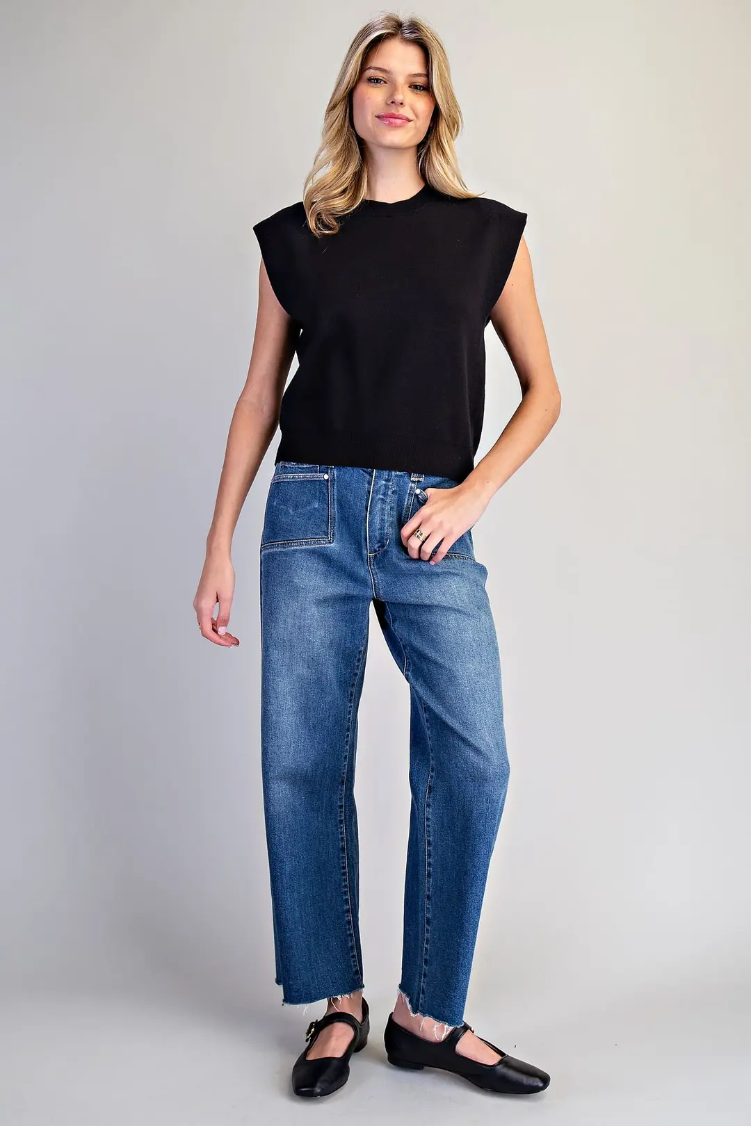 Woman wearing a black sleeveless Elle Extended Shoulder Knit Top with blue jeans.