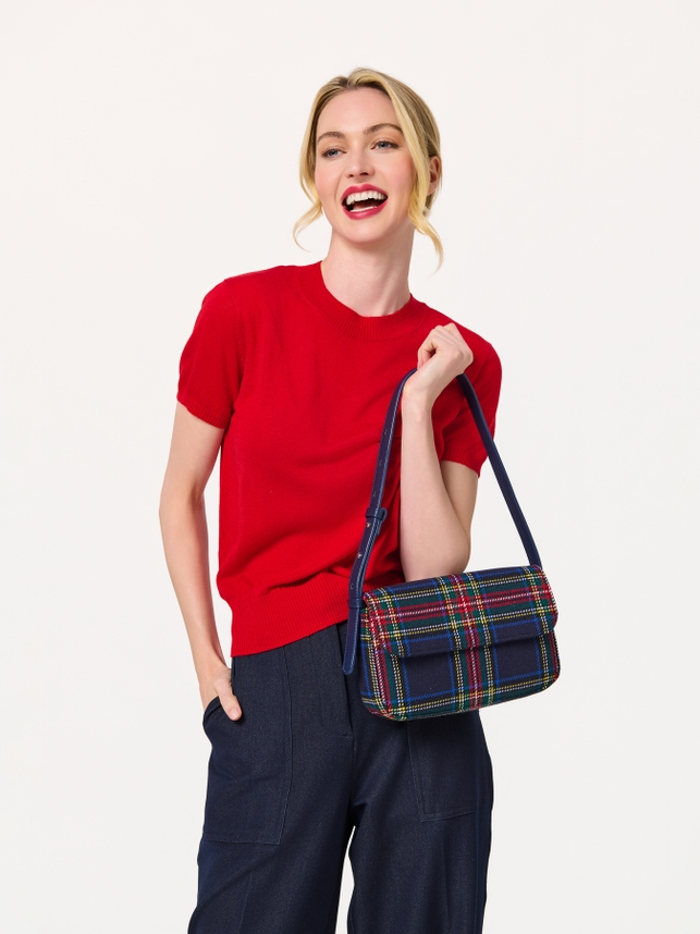 Woman wearing a red short-sleeve sweater and navy pants holding a plaid Scottie Shoulder Bag.