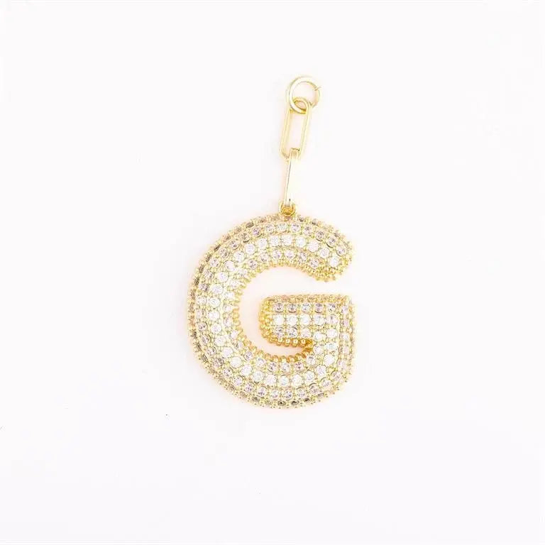 Heather-colored charm bag with gold plating, pave crystal accents, initial engraving option, and attached extender chain.