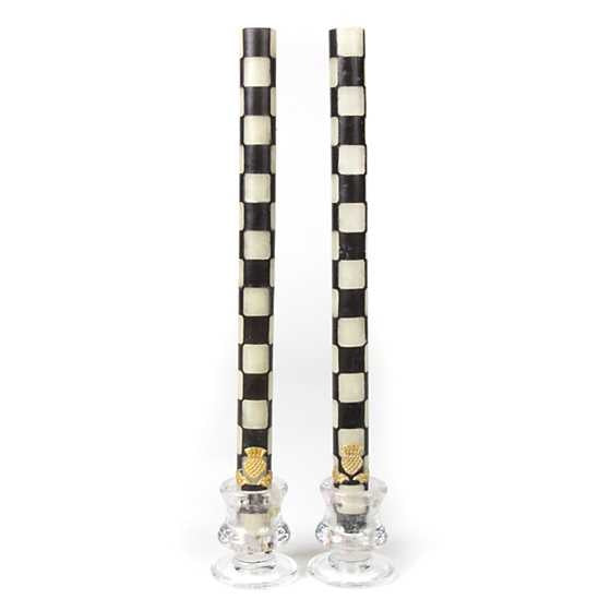Set of two black dinner candles with ivory checkered wax patterns in cylindrical glass holders.