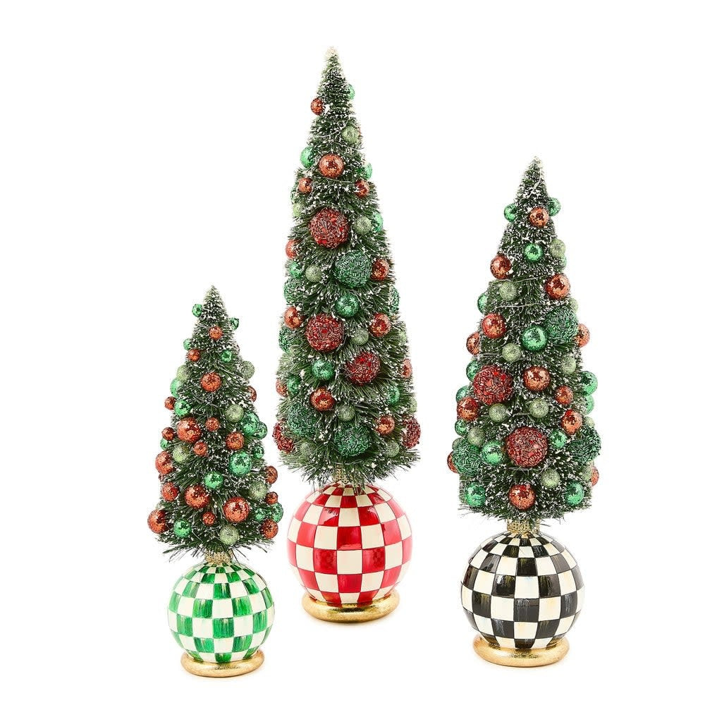 Illuminated resin bottle brush tree with frost-covered branches, red and green baubles on a tabletop.