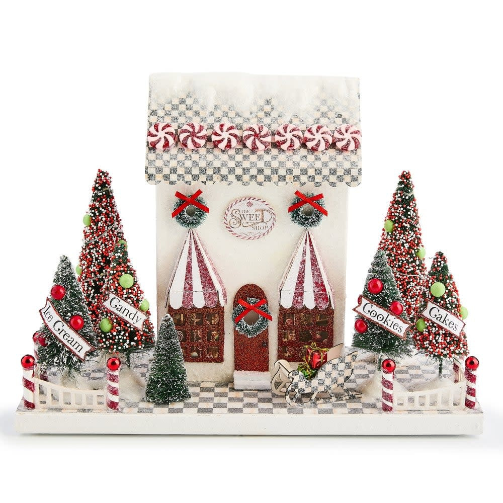 Illuminated paper house shaped like a snow-covered sweet shop with peppermint garlands and candy trees.