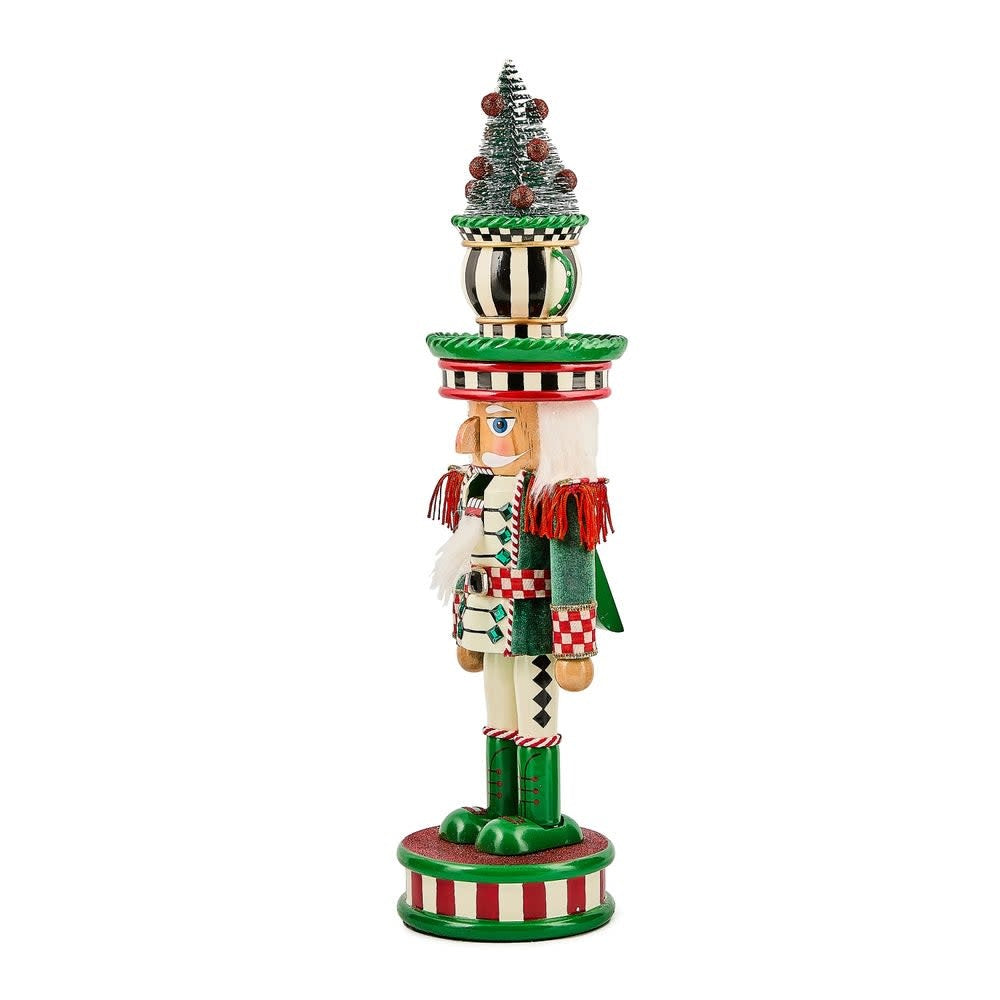 Wooden teacup nutcracker with red fabric accents standing upright.