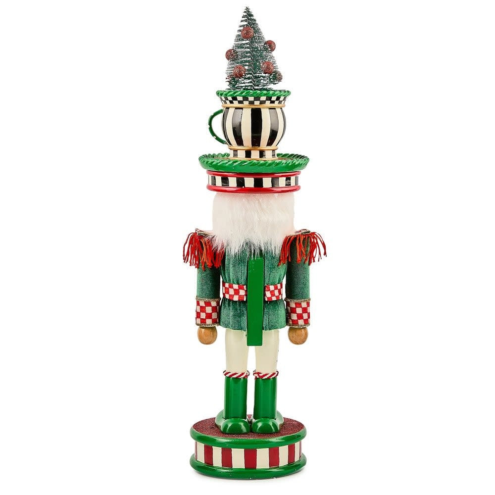 Wooden teacup nutcracker with a festive red hat and blue coat standing on a decorative base.