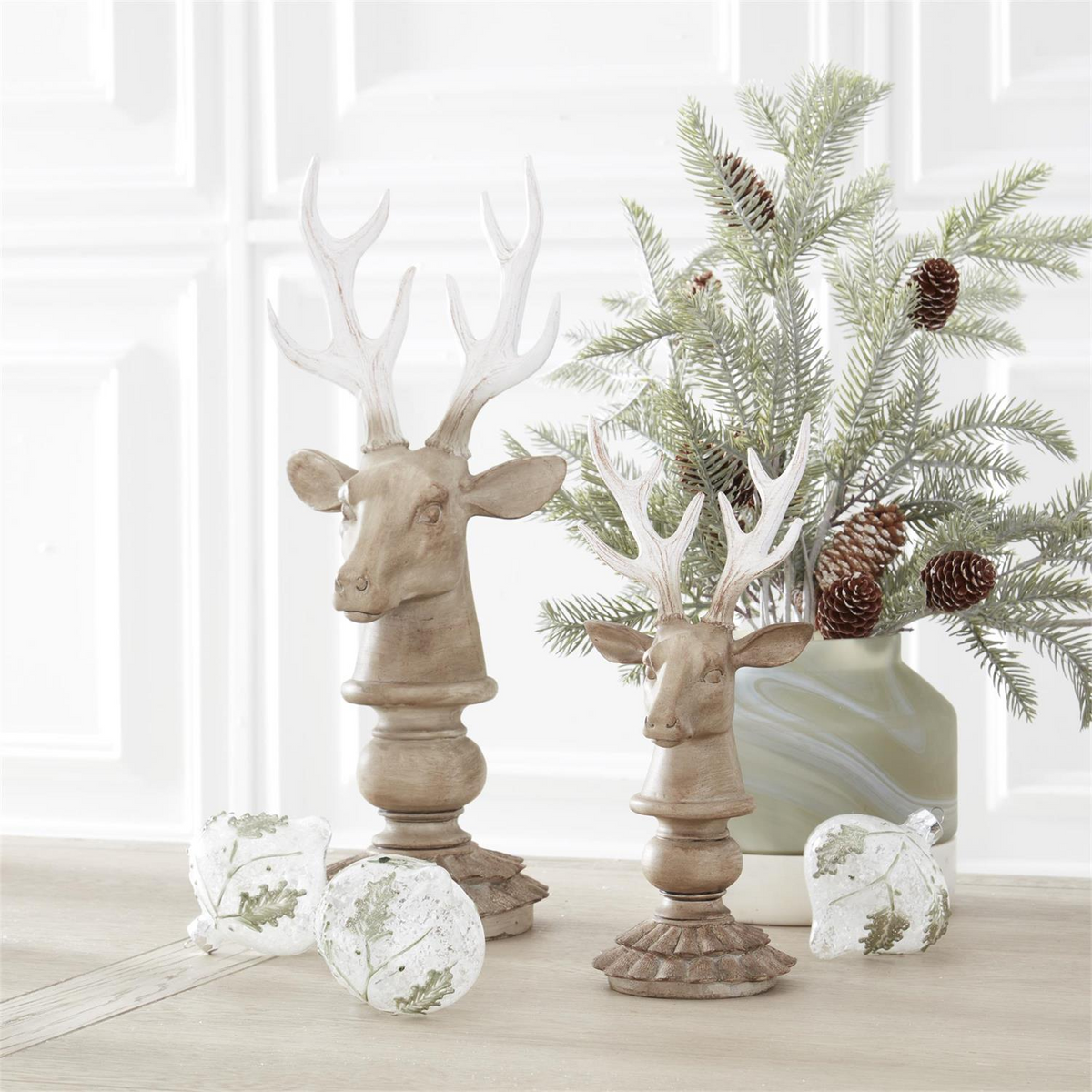 Two cream and taupe resin deer busts with a wood-look finish on scalloped bases.