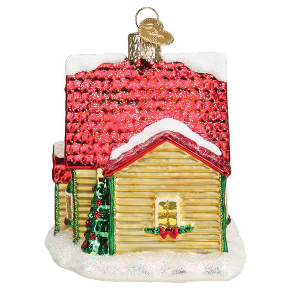 Glass Christmas cottage ornament with white walls, red roof, green door, snow-covered ground, and festive lights.