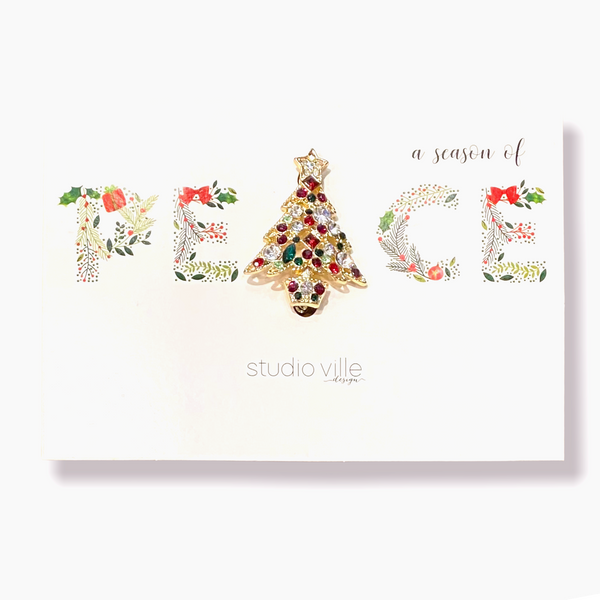 Metal Christmas pin featuring a peace symbol with glittery red and green festive glitz.