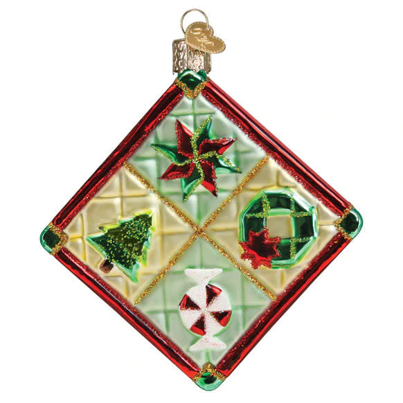 Glass Christmas ornament shaped like a quilt with red and green patchwork pattern.