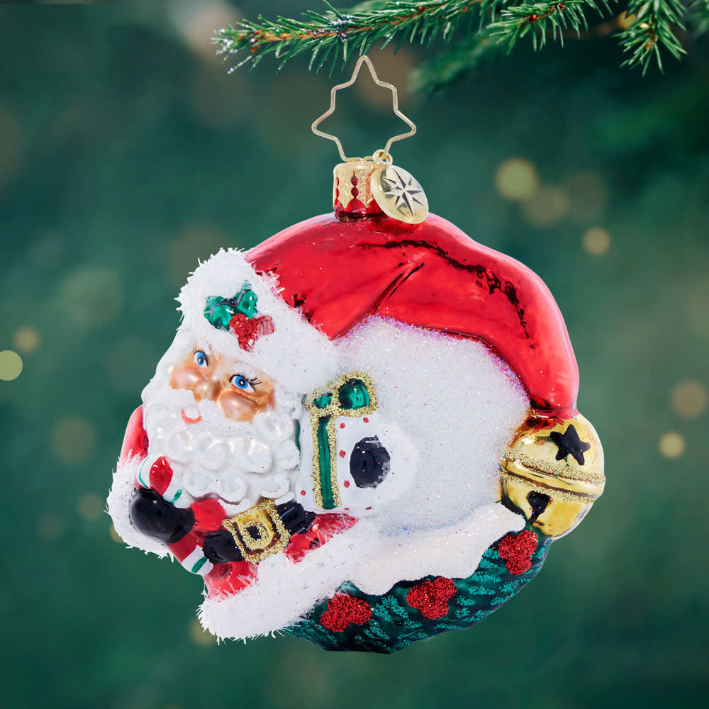 Red Santa wreath ornament with rosy cheeks, twinkling eyes, classic hat silhouette on a green background.