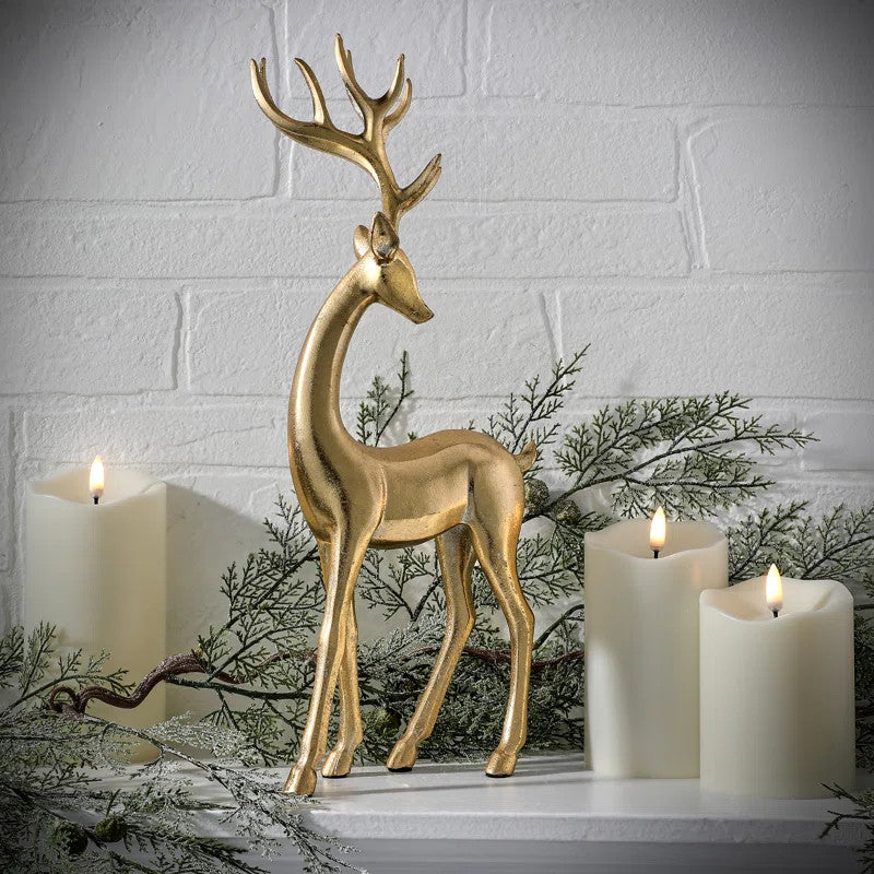 15-inch gold resin standing elegant deer figurine on a mantel with candles and greenery.