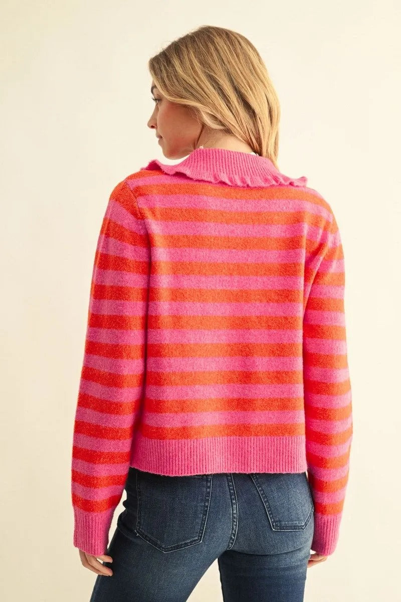 Back view of a woman wearing a pink and orange striped long sleeve button-down sweater cardigan.