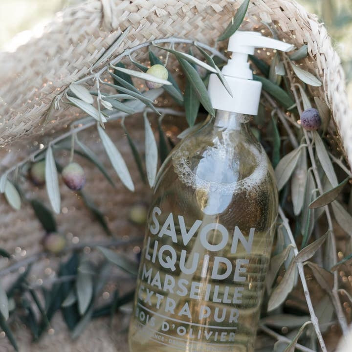 Glass pump bottle containing liquid Marseille soap in olive wood scent with citrus notes.