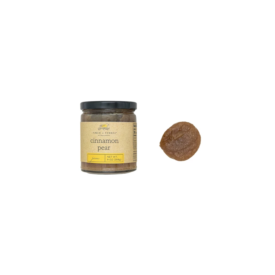 Glass jar of cinnamon pear jam with a white label featuring red text.