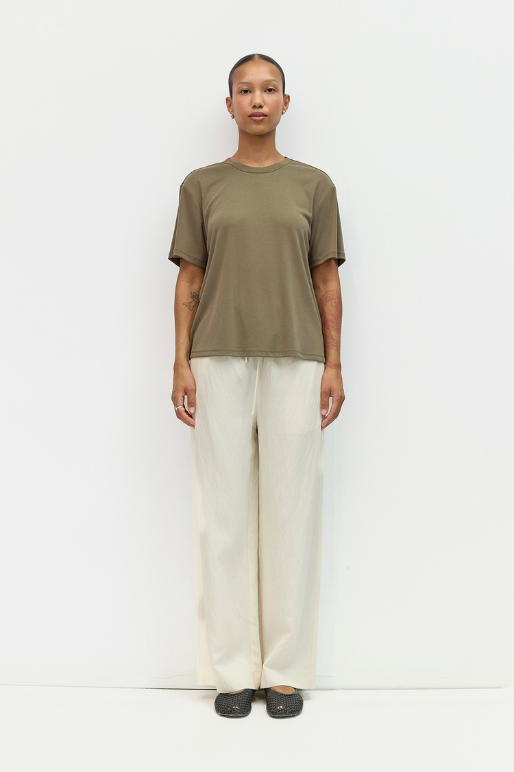A person wearing The Jodi Pants, which are cream wide-leg trousers with a drawstring waist.