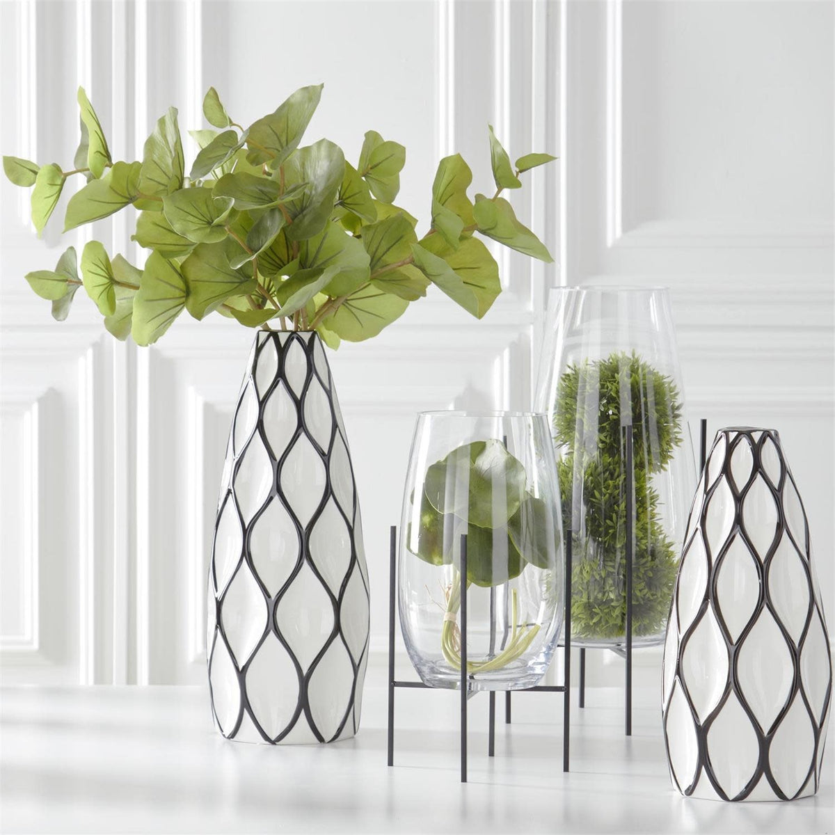 Clear glass floating vase on a dark metal stand with an open circular base.