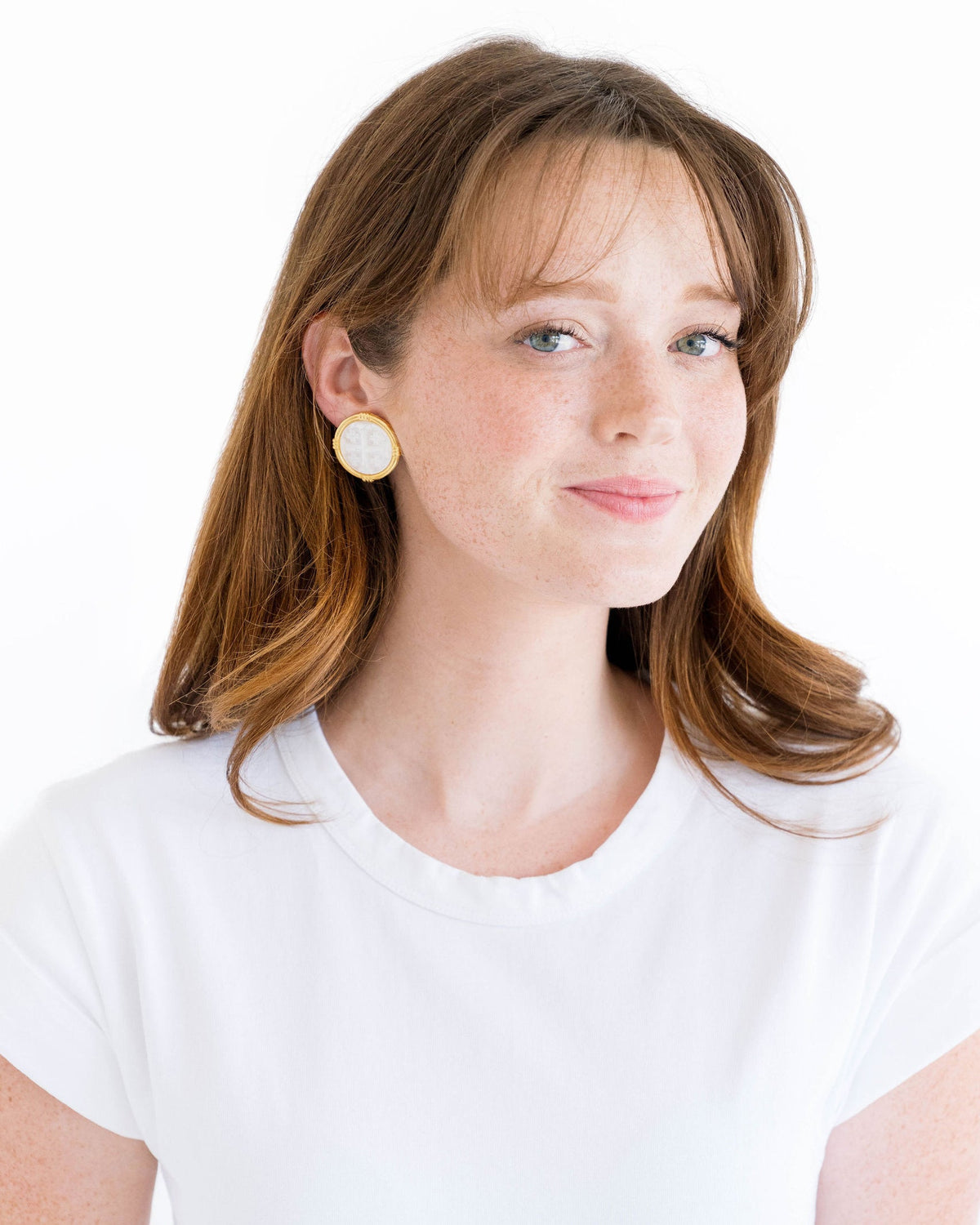 Woman wearing Ida Jerusalem Cross Studs, 1-inch gold and mother of pearl earrings.