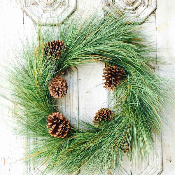 24-inch giant pine wreath with long green needles and five natural sugar pine cones on a white door.