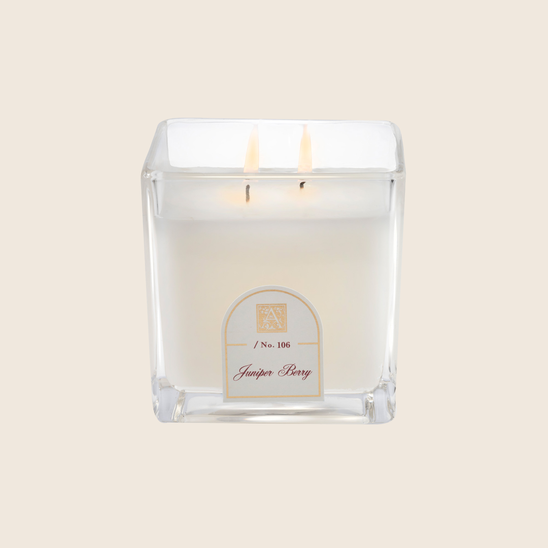 12 oz Juniper Berry scented white wax candle in a square cube glass jar with two lit wicks.