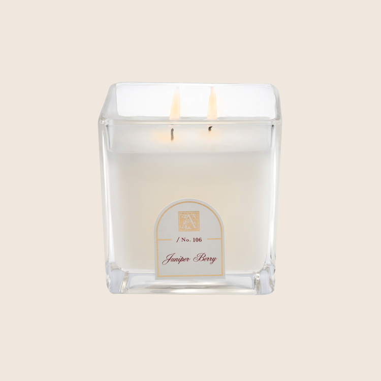 12 oz Juniper Berry scented white wax candle in a square cube glass jar with two lit wicks.