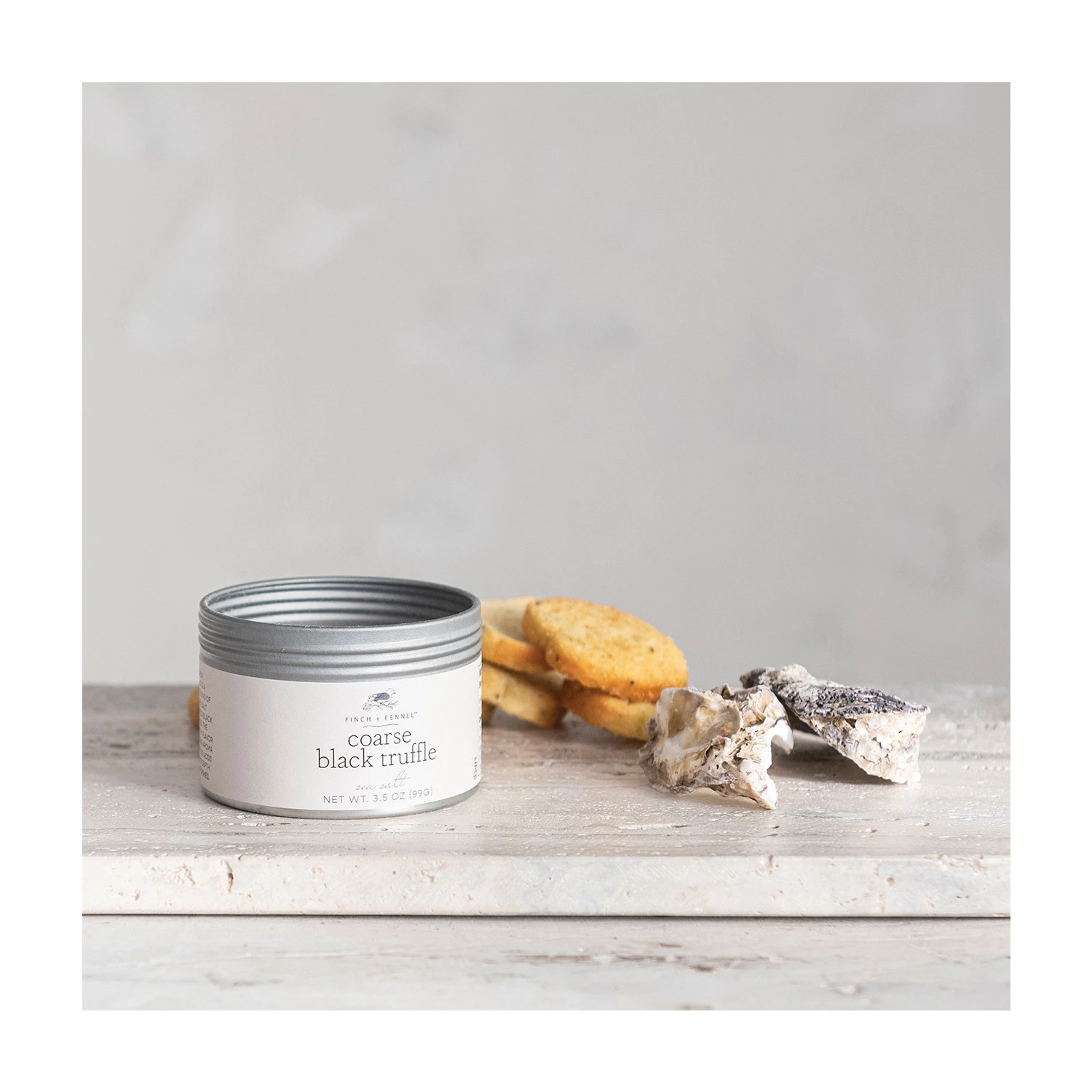 Coarse black truffle sea salt in a clear glass jar with a white lid