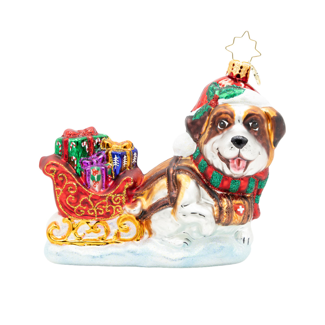 Glass Christmas ornament of a Saint Bernard dog pulling a red sleigh filled with colorful gifts.