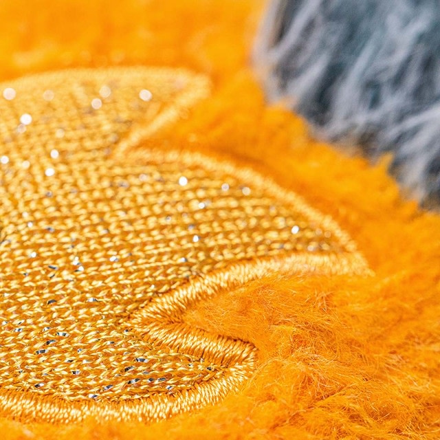 Close-up of a gold glittery embroidered star on bright orange fuzzy fabric.