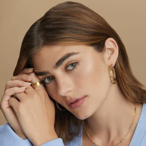 Gold-plated medium hoop earrings featuring vintage-inspired scrollwork with a quarter-inch width and one-and-a-quarter inch drop.