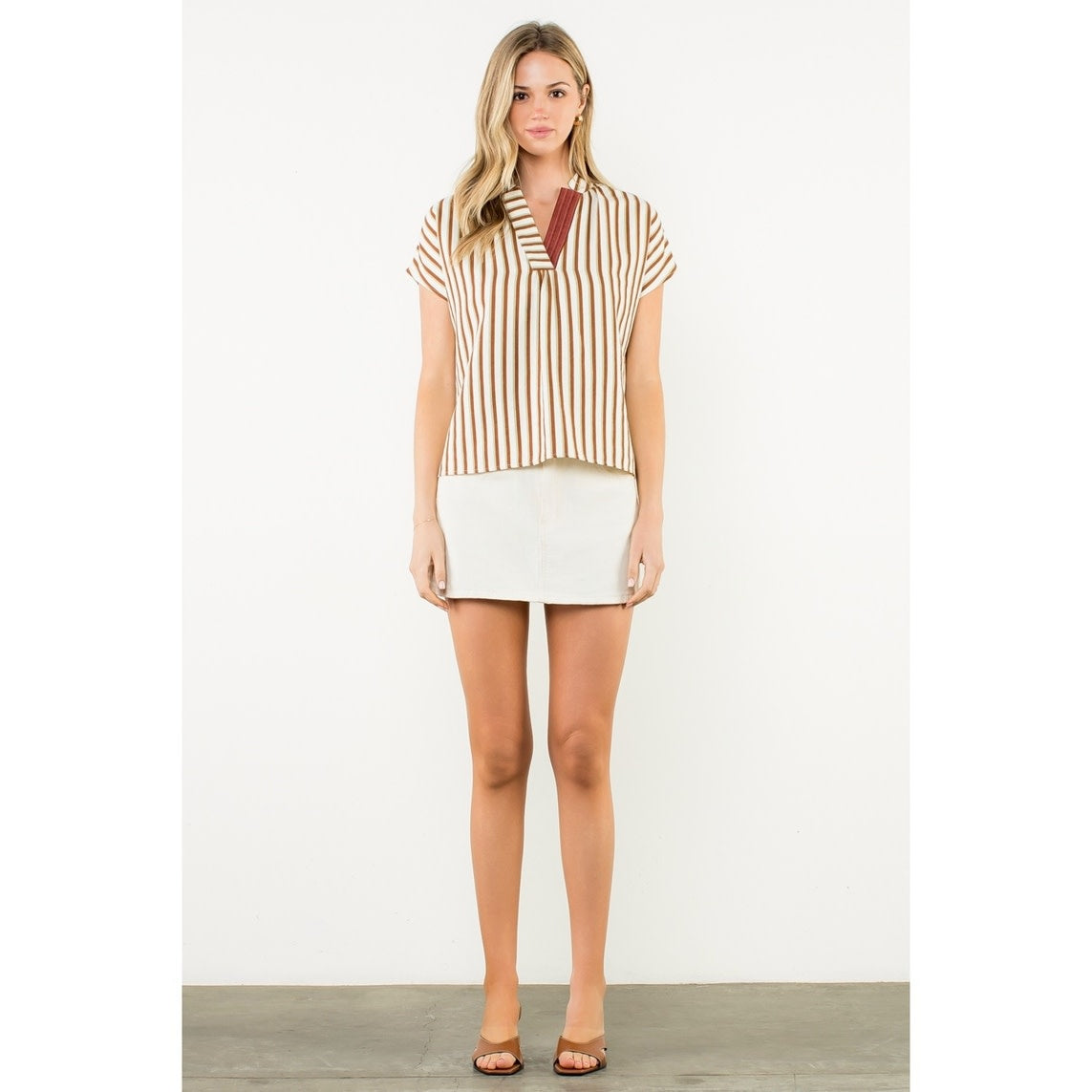 Front view of a women's woven striped top with contrast V-neck trim in polyester and nylon.