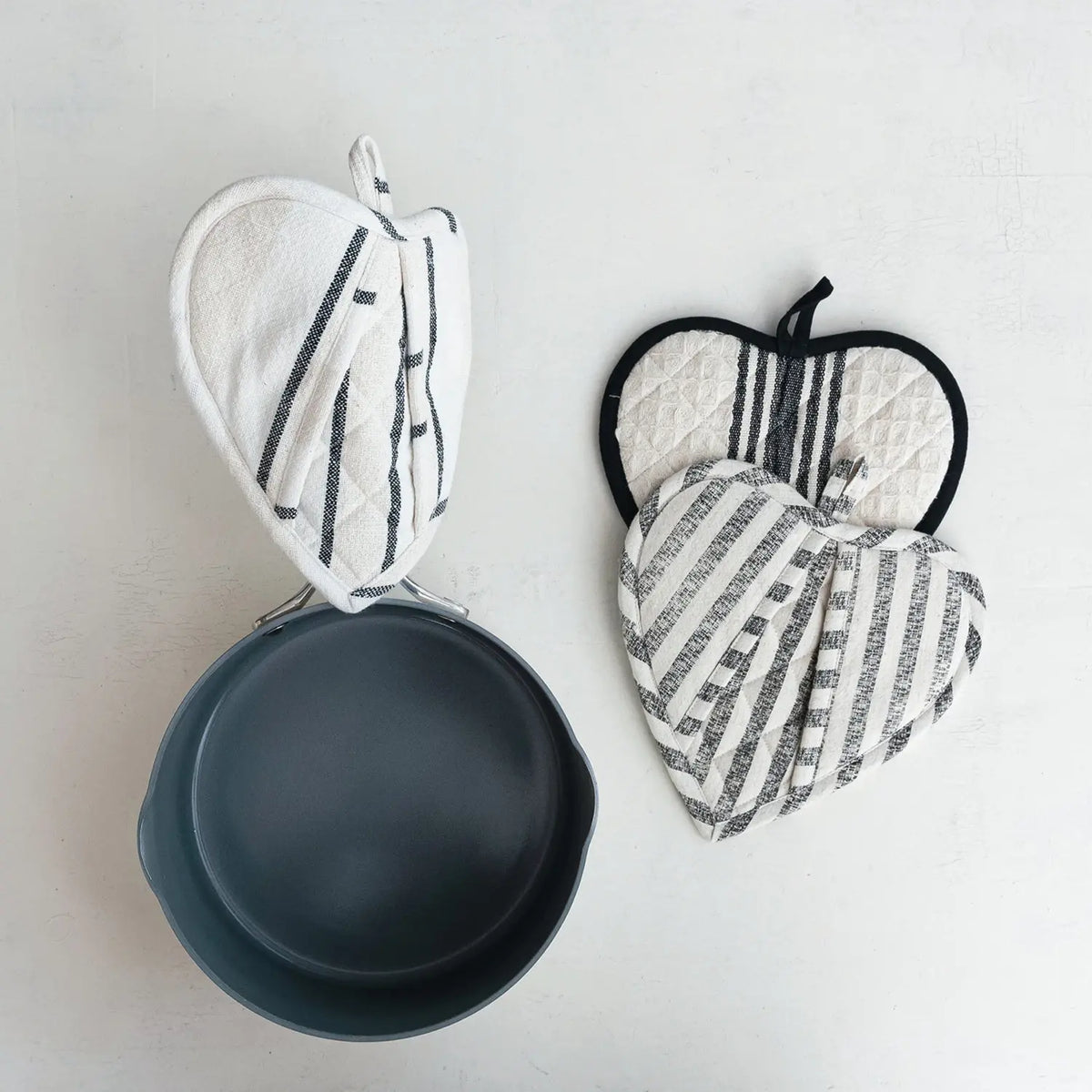 Cotton quilted heart-shaped pot holder in natural fabric with visible stitching texture.