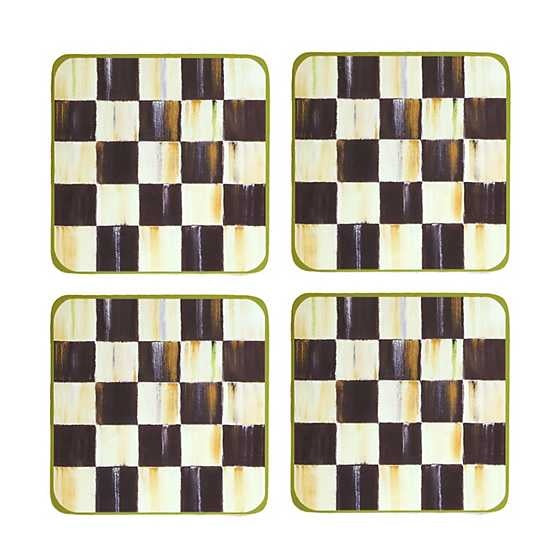 Set of four cork-backed coasters with black-and-white checked pattern on a hard-board surface.