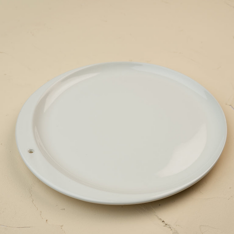 A minimalist white ceramic Celebration Circle plate with a single small hole on the rim.