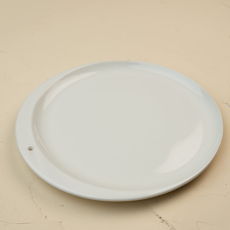 A minimalist white ceramic Celebration Circle plate with a single small hole on the rim.