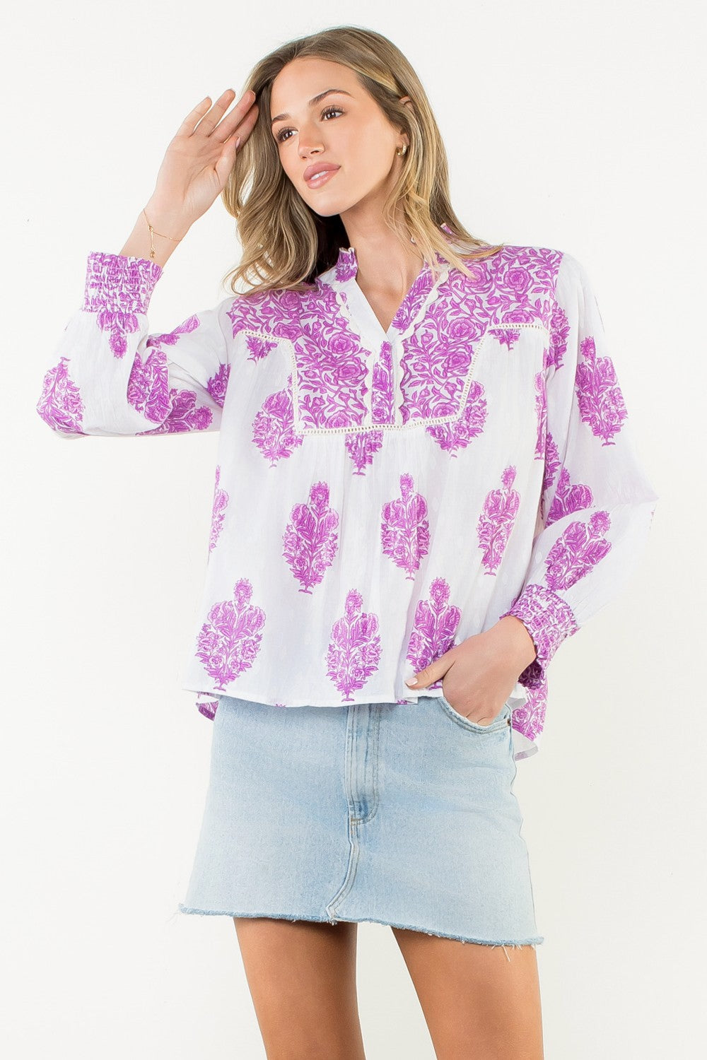 Woman wearing the Amy Long Sleeve Flower Print Top in white with purple floral patterns.