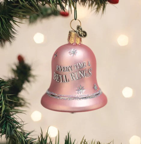 Pink bell-shaped glass ornament with 'EVERY TIME A BELL RINGS' text hanging on a Christmas tree.