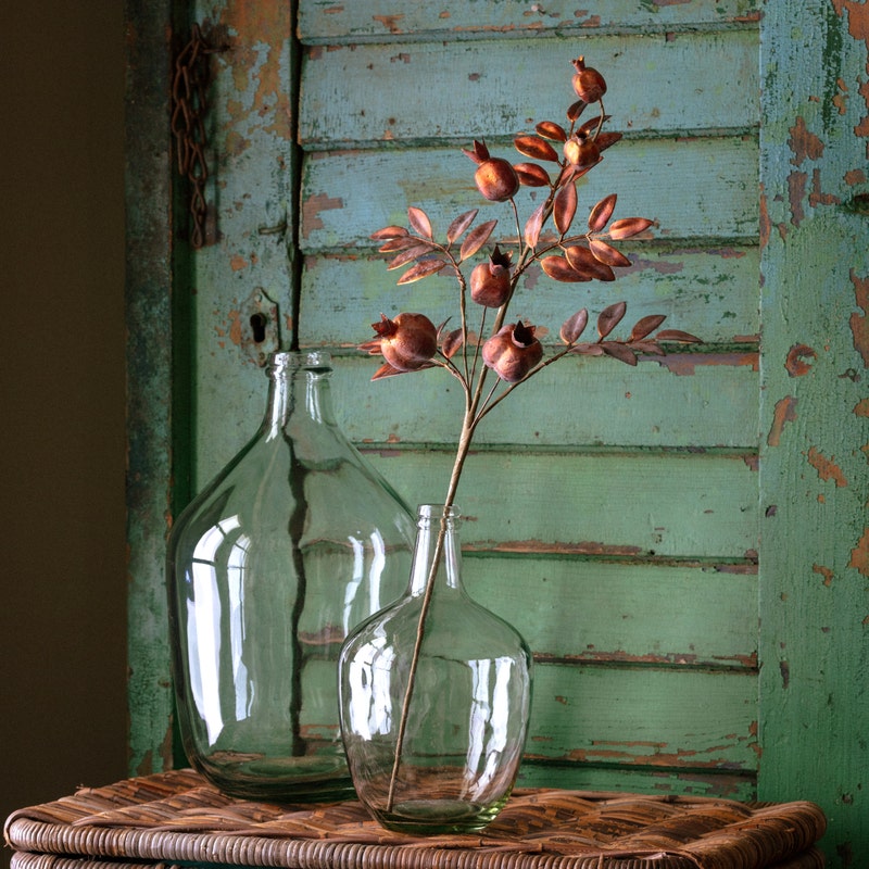 Antique Copper Pomegranate Stem with metallic leaves and fruit in a clear glass vase.