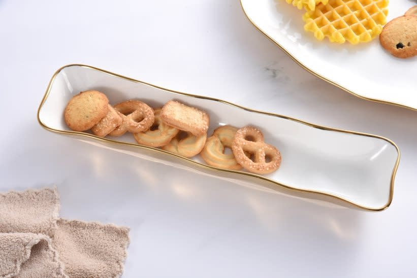 Curvy white porcelain cracker tray with smooth gold titanium handles.