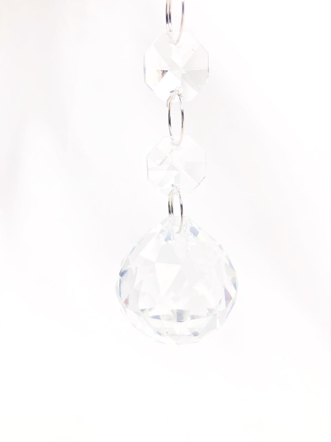 Glass crystal drop ornament with faceted jewel ball hanging from a string light fixture.