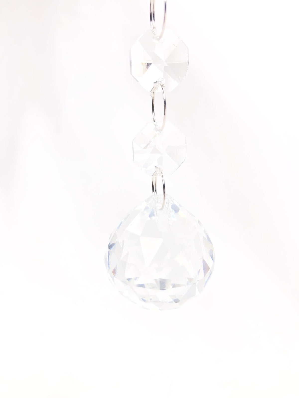 Glass crystal drop ornament with faceted jewel ball hanging from a string light fixture.