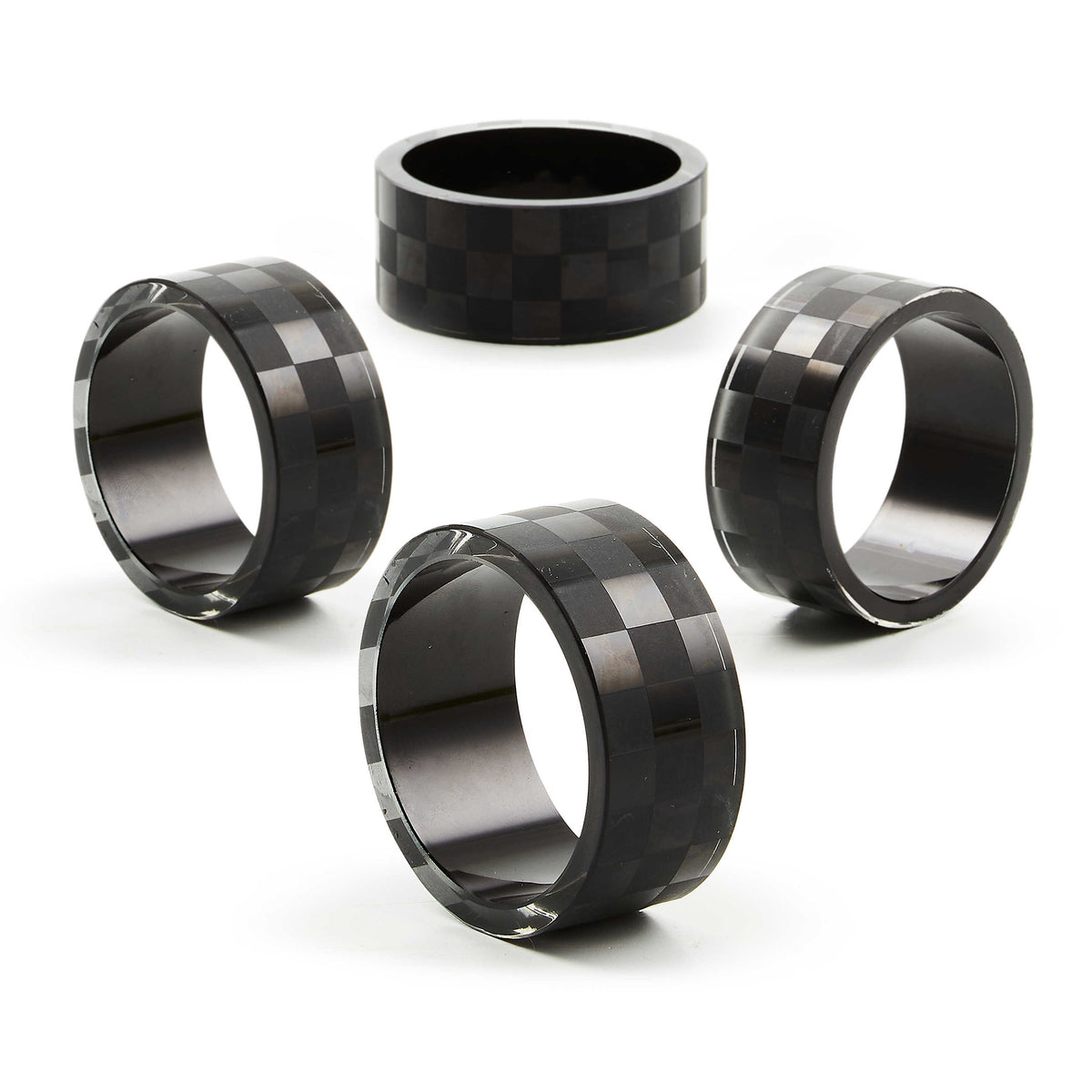 Set of four black glass napkin rings with a subtle checkered pattern on a white background.
