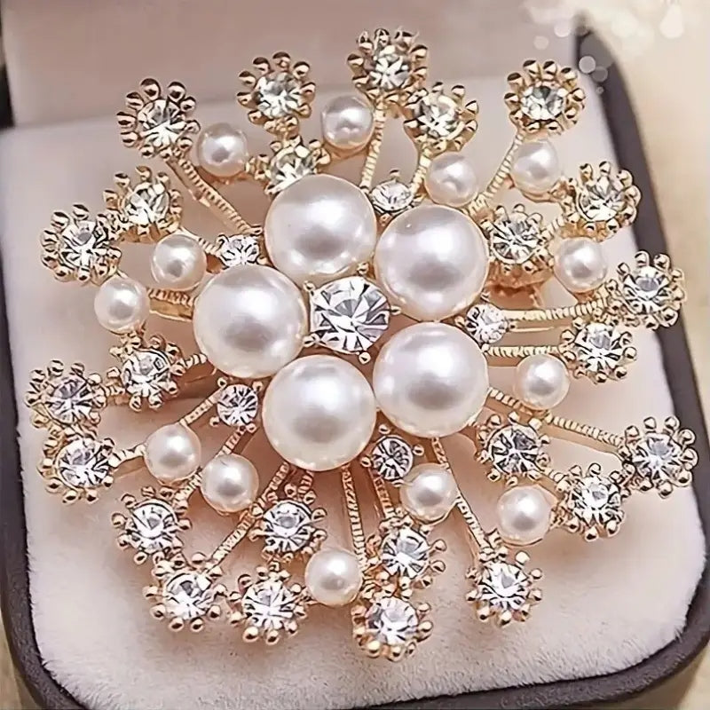 Silver-tone snowflake brooch featuring sparkling clear rhinestones in a symmetrical geometric pattern.