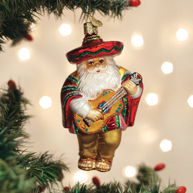 Papa Noel glass ornament featuring Santa in a sombrero and poncho playing a guitar on a tree.