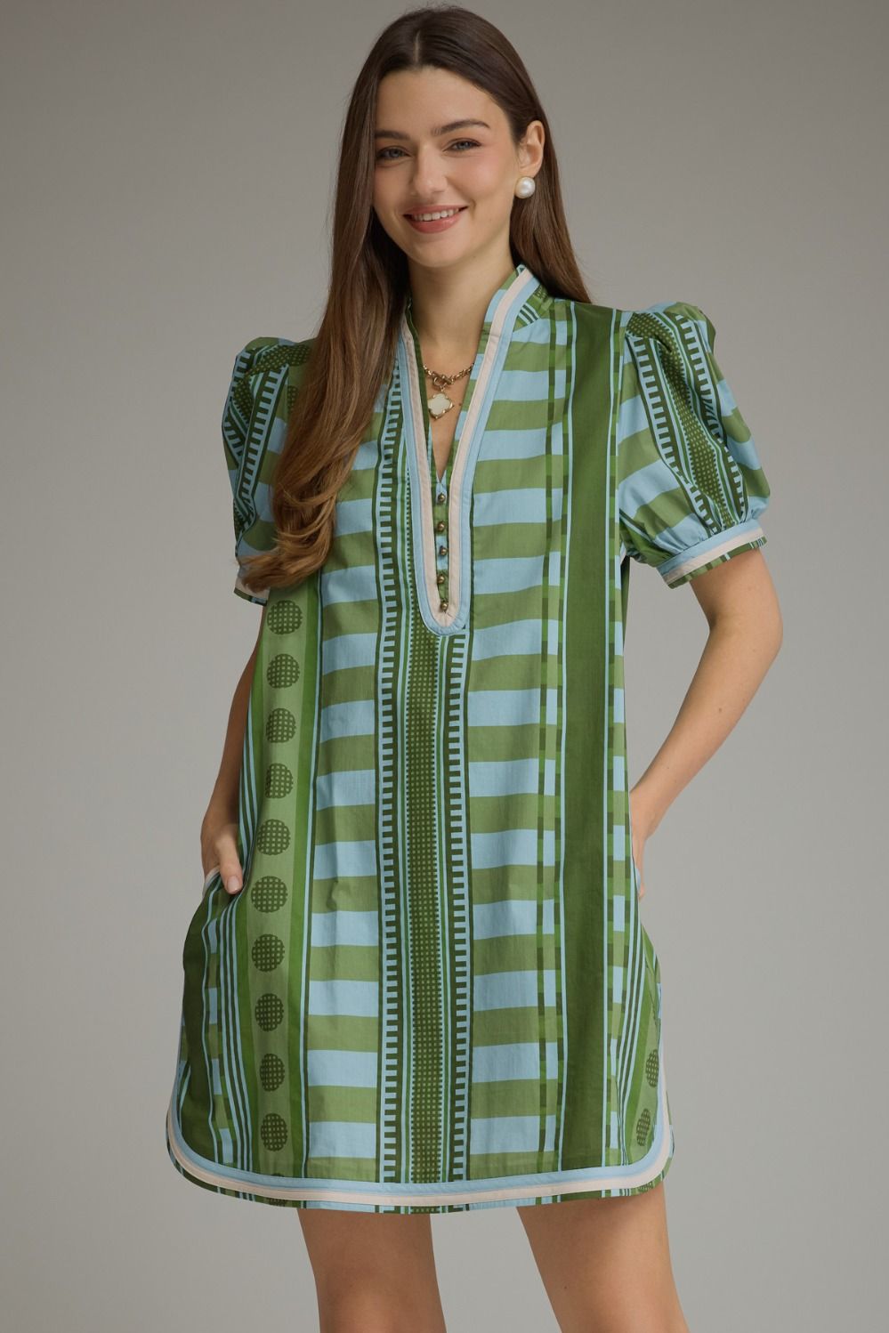 Woman wearing the Gabrielle green and blue striped mini dress with puff sleeves and V-neckline.