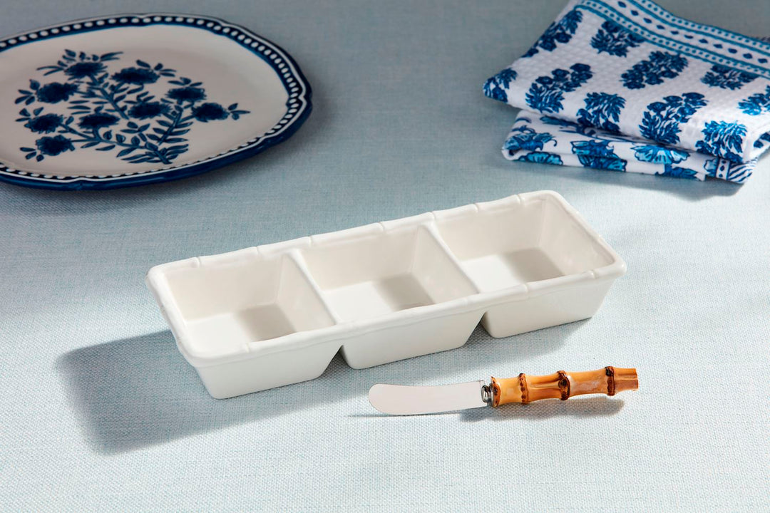 White ceramic triple tidbit dish with bamboo-style trim and a matching bamboo-handled spreader.