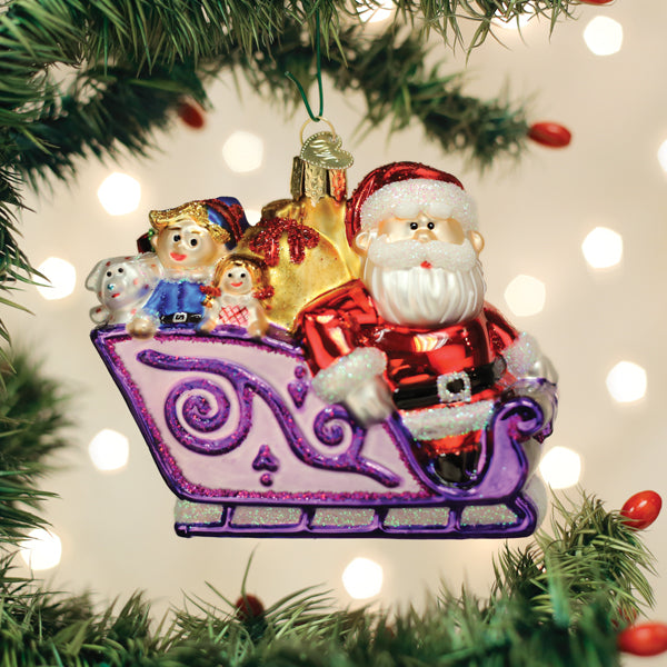 Glass Santa and friends ornament featuring Santa in a purple sleigh with toys on a Christmas tree.